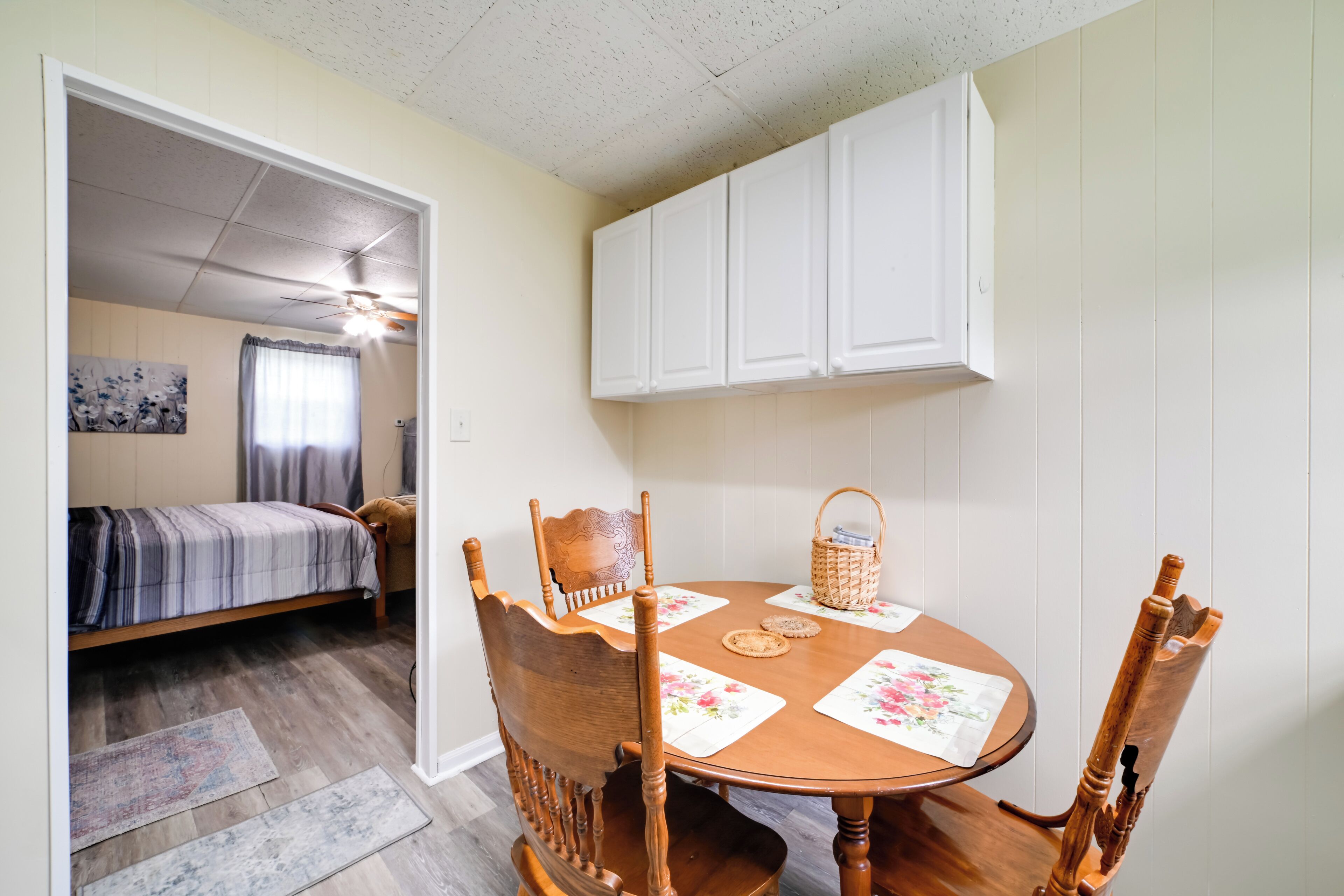 A cozy room with a bed, a dining table with chairs, and a ceiling fan.