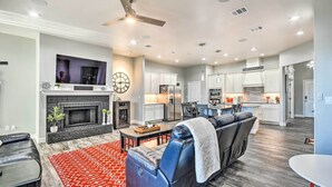 A modern living room with a fireplace, a ceiling fan, and a dining area. - Modern Amarillo House w/ Fire Pit + Hot Tub! (Amarillo)