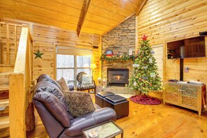 A cozy log cabin interior with a fireplace, a Christmas tree, leather seating, and a television. - Mossy Rock Retreat: Cabin Near Desoto Park! (Mentone)
