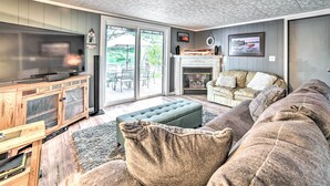 A modern living room with a large television, a fireplace, and a comfortable seating area. - Riverfront Home w/ Dock ~ 6 Mi to Cheboygan! (Cheboygan)