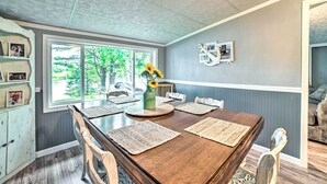 A dining area with a wooden table, beige placemats, and a vase with sunflowers. - Riverfront Home w/ Dock ~ 6 Mi to Cheboygan! (Cheboygan)