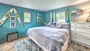 A bedroom with a bed, dresser, surfboards, and a window. - Riverfront Home w/ Dock ~ 6 Mi to Cheboygan! (Cheboygan)