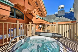 Un jacuzzi con cubierta de madera y valla, rodeado por un edificio con chimenea y ventana.