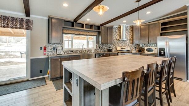 A modern kitchen with a large island, wooden chairs, and built-in appliances. - Spacious Tierra Amarilla Ranch House w/ Deck! (Tierra Amarilla)