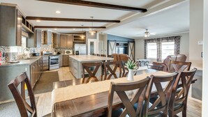 A spacious kitchen with wooden beams, a dining area with a large table and chairs, and a living area with a sofa and curtains. - Spacious Tierra Amarilla Ranch House w/ Deck! (Tierra Amarilla)