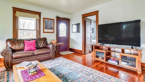 A living room with a leather sofa, a coffee table, a flat-screen TV, and a wooden entertainment center.
