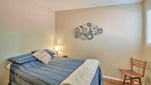 Een slaapkamer met een bed, nachtkastje, stoel en decoratieve wandversiering.