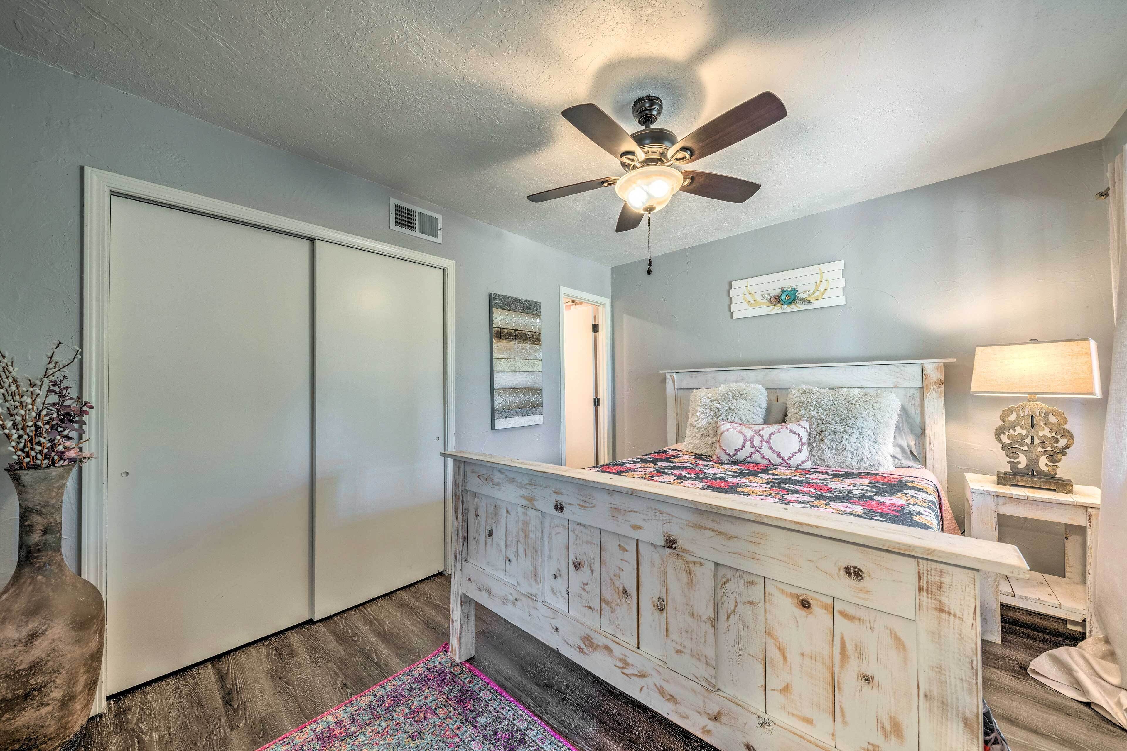 A bedroom with a wooden bed, a ceiling fan, a nightstand, and a door.