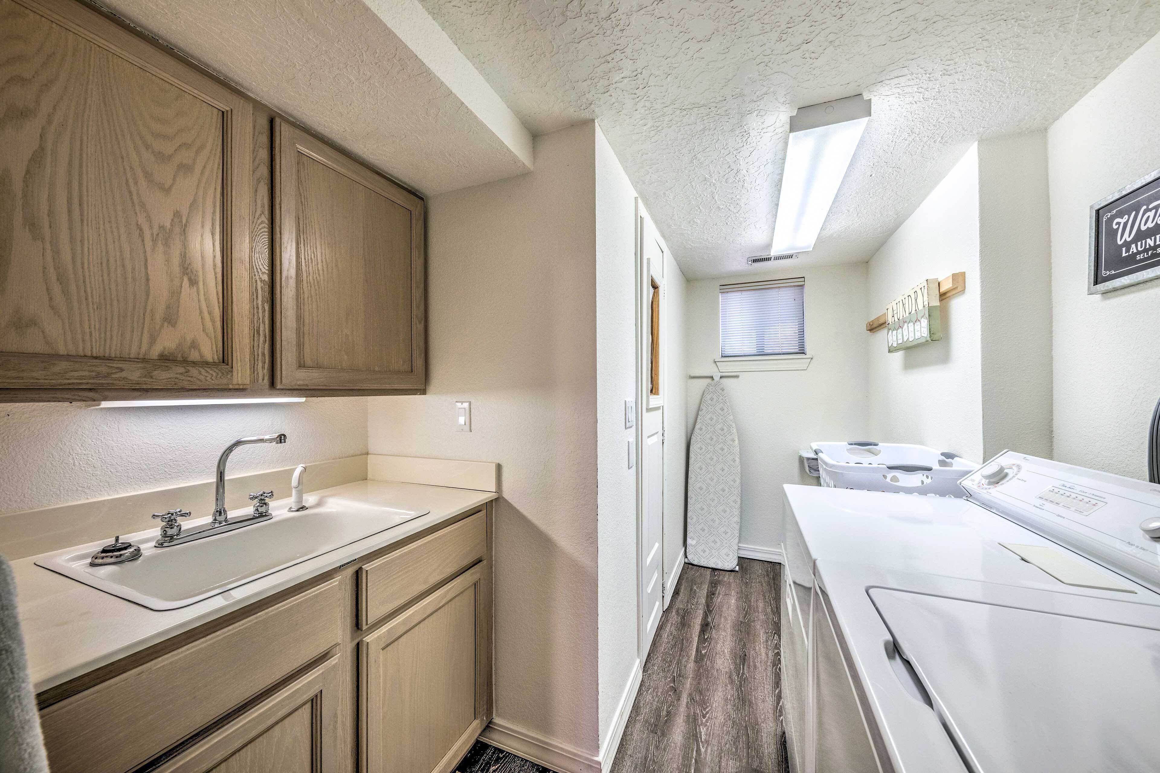 A compact kitchen with wooden cabinets, a white sink, and a built-in ironing station.