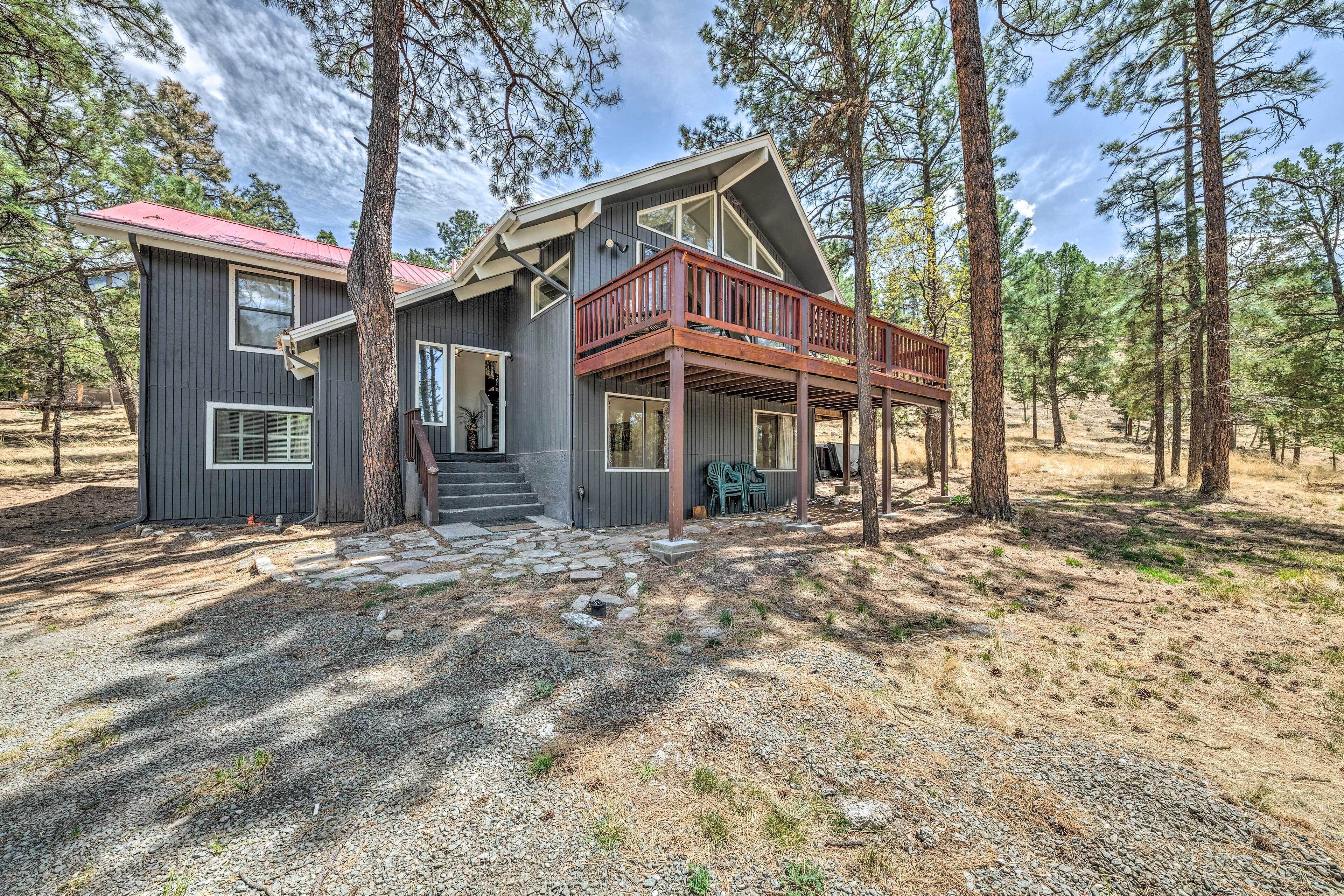 A two-story cabin with a wooden deck and a stone pathway leading to the entrance.