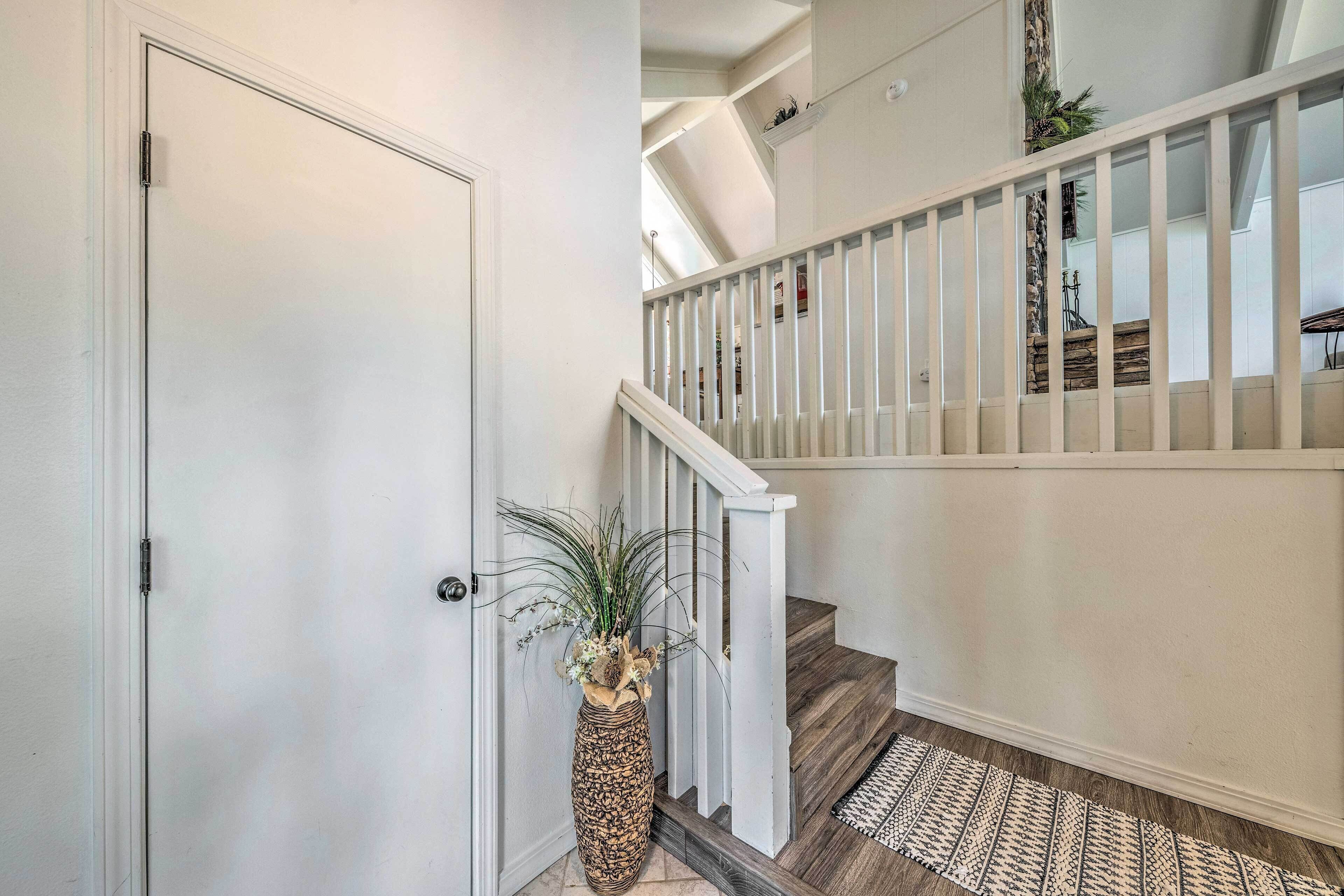 A staircase with white railings and a patterned rug at the bottom.