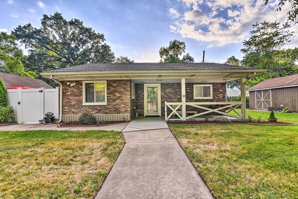 A single-story brick house with a covered porch, a front door, and a small attached garage.