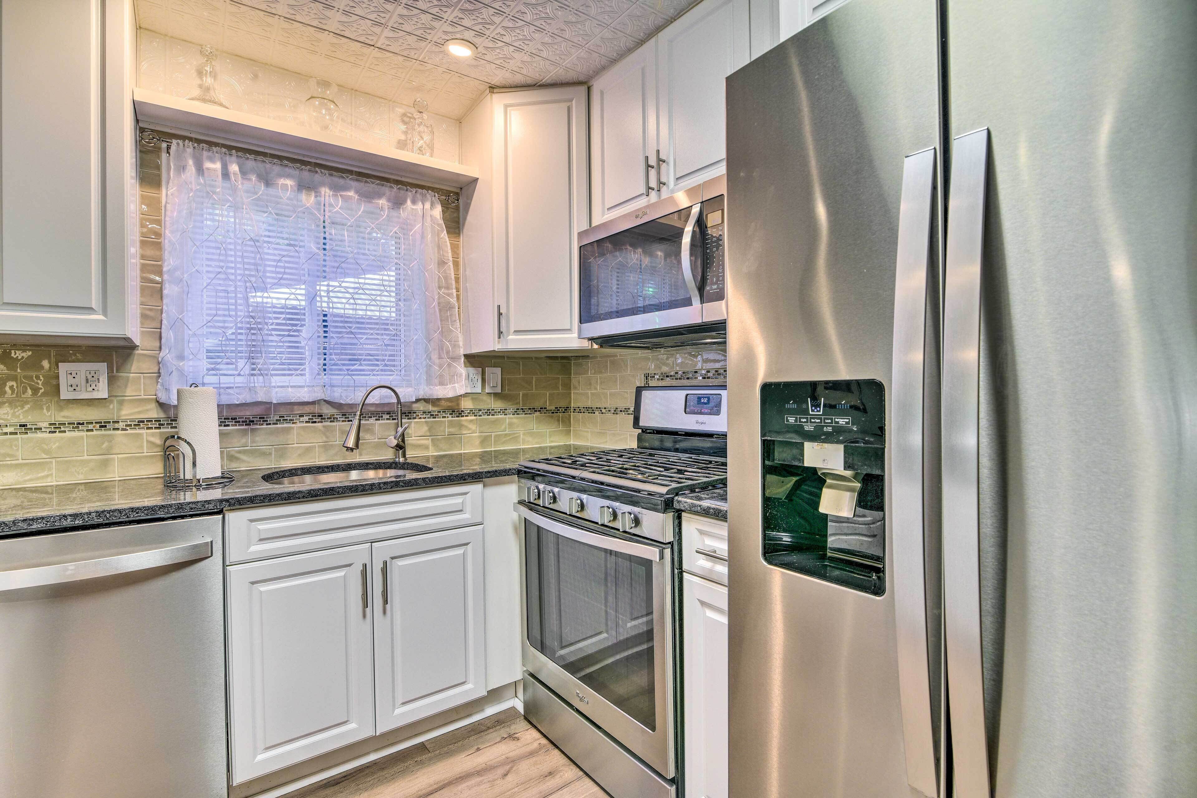 A kitchen with white cabinets, a stainless steel refrigerator, a microwave, and an oven.