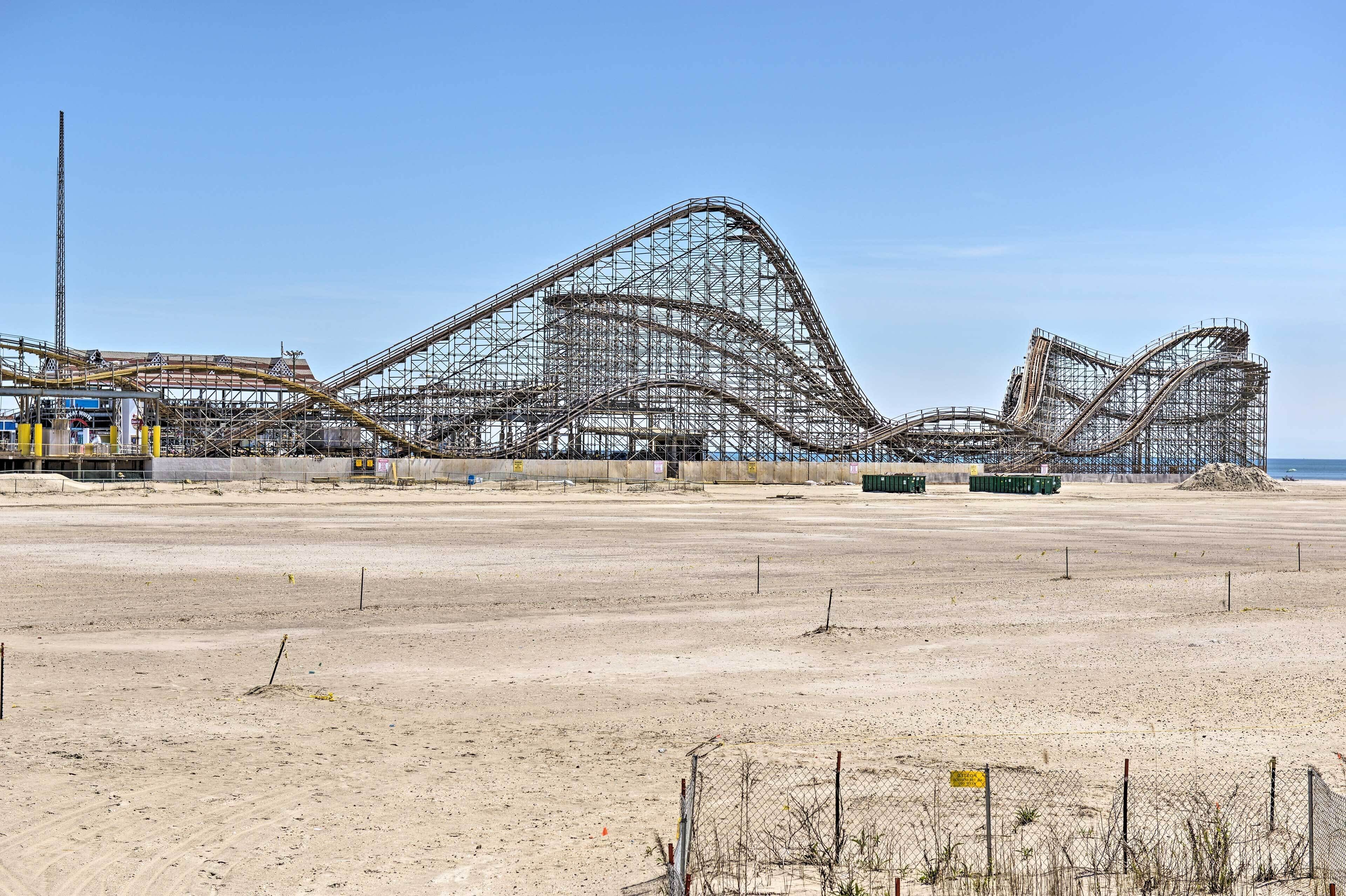 A roller coaster under construction with a clear sky and sandy beach in the background.