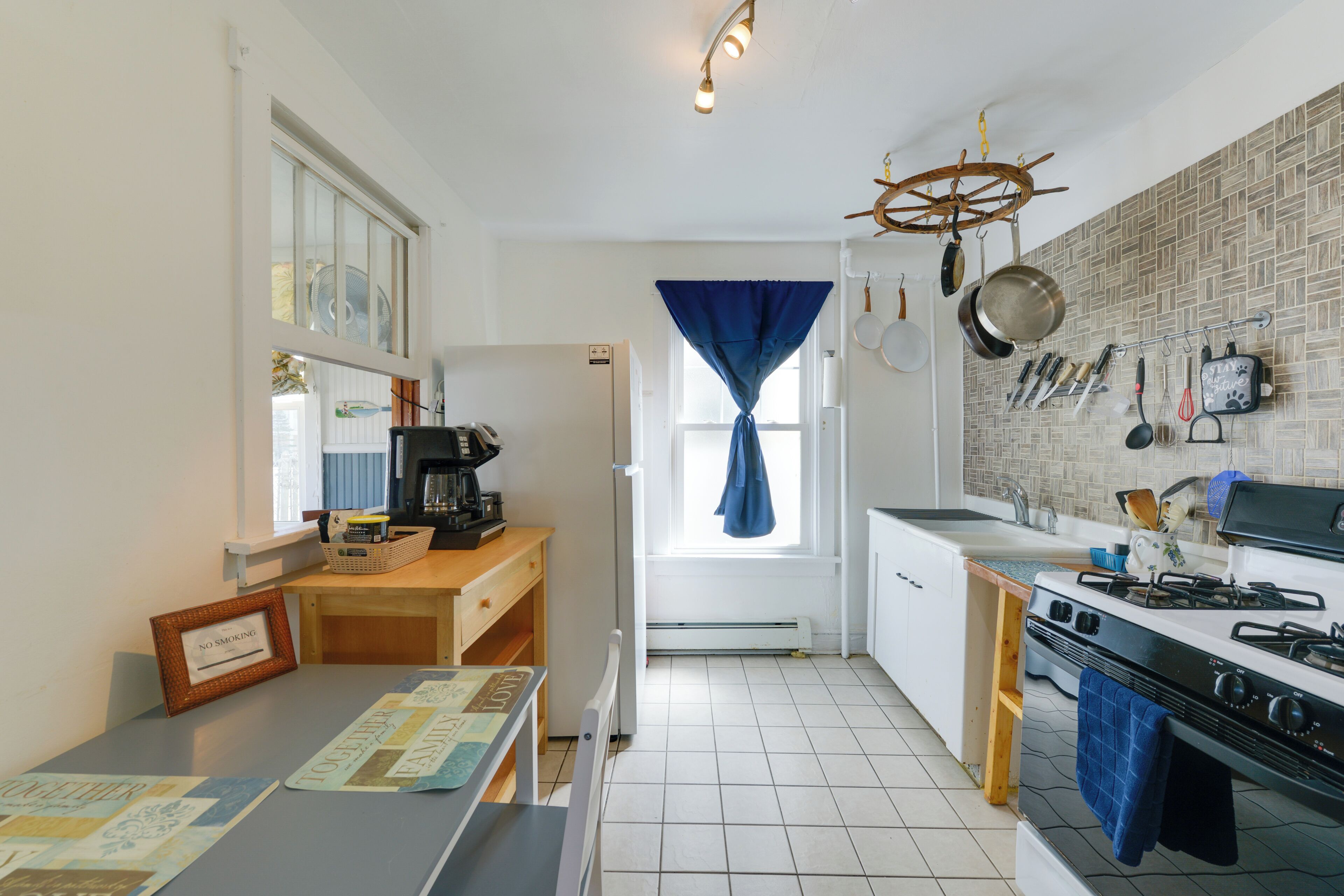 Cocina compacta con estufa, pileta y ventana con cortinas.