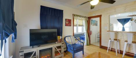Una sala de estar con televisor, chimenea, mesa de comedor y dos sillas.