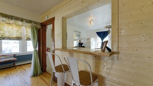 A wooden interior with two white metal chairs, a wooden counter, and a large mirror. - Wildwood Apartment - Porch & Enclosed Sunroom! (Wildwood)