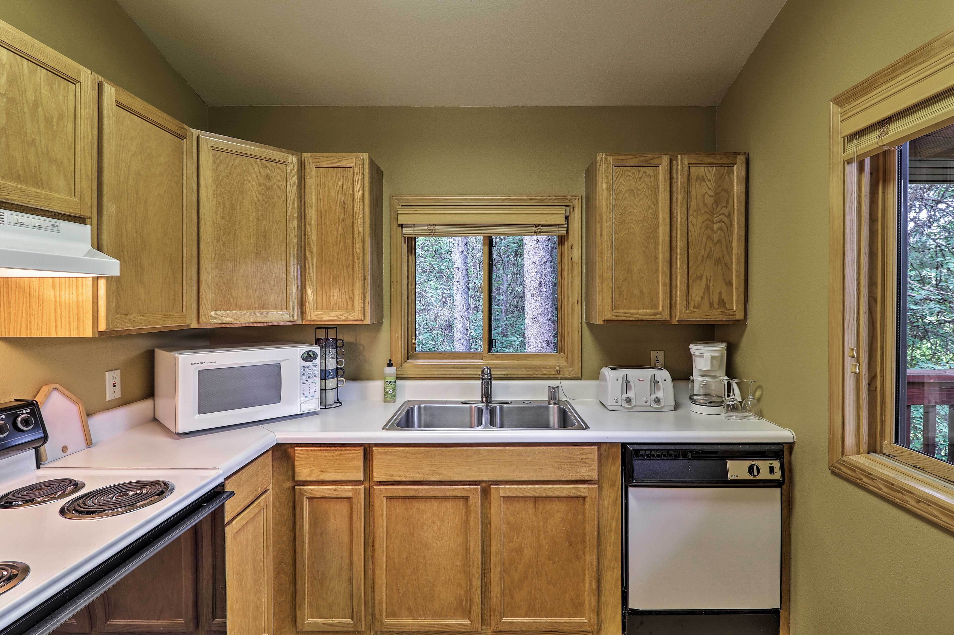 A compact kitchen with wooden cabinets, a microwave, a toaster, and a dishwasher.