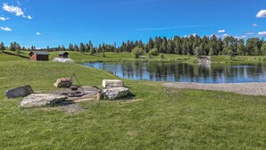 A serene lakeside setting with a small cabin and a fishing area. - Trego Cabin w/ Mountain Views & Lake Access! (Trego)