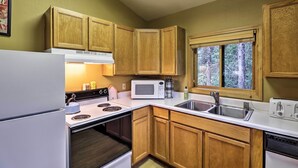 A compact kitchen with wooden cabinets, a microwave, a stove, and a sink. - Trego Cabin w/ Mountain Views & Lake Access! (Trego)