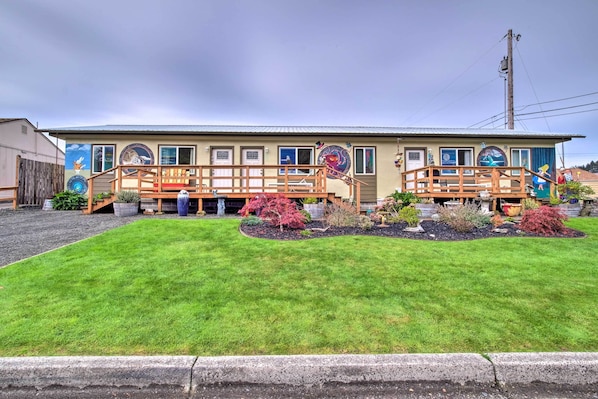 A motel with a covered outdoor area, a well-maintained lawn, and various potted plants.