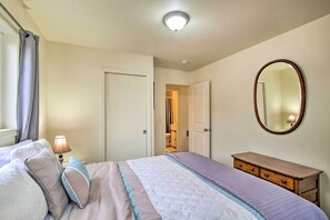 A bedroom with a bed, a dresser, a mirror, and a door leading to a bathroom. - Winchester Bay Apt Near Dunes & State Parks! (Reedsport)