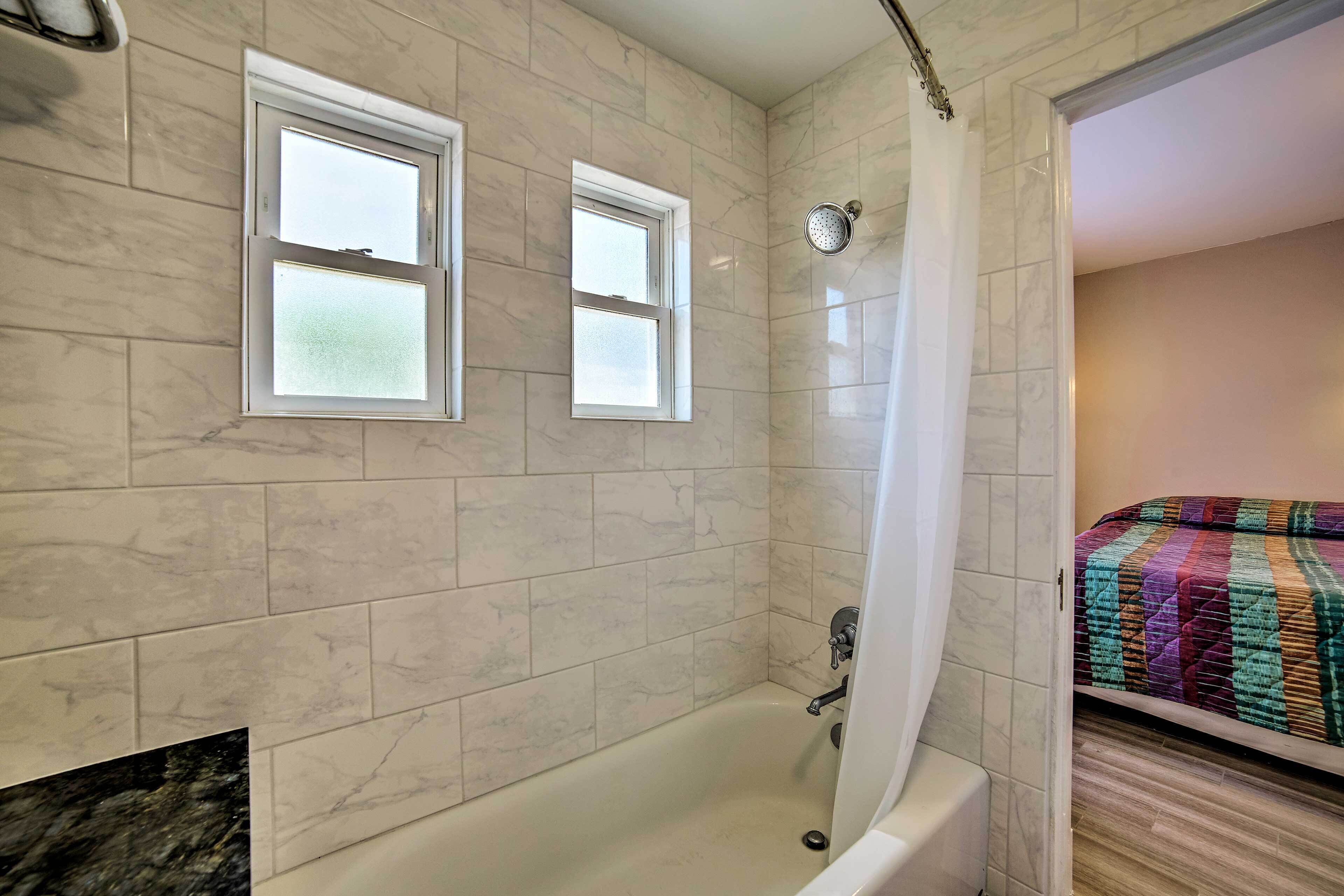 A bathroom with a bathtub, two windows, and a shower curtain.