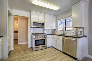 A modern kitchen with stainless steel appliances, white cabinetry, and a wooden floor. - Walk to Beach: Condo w/ Patio on Catalina Island (Avalon)