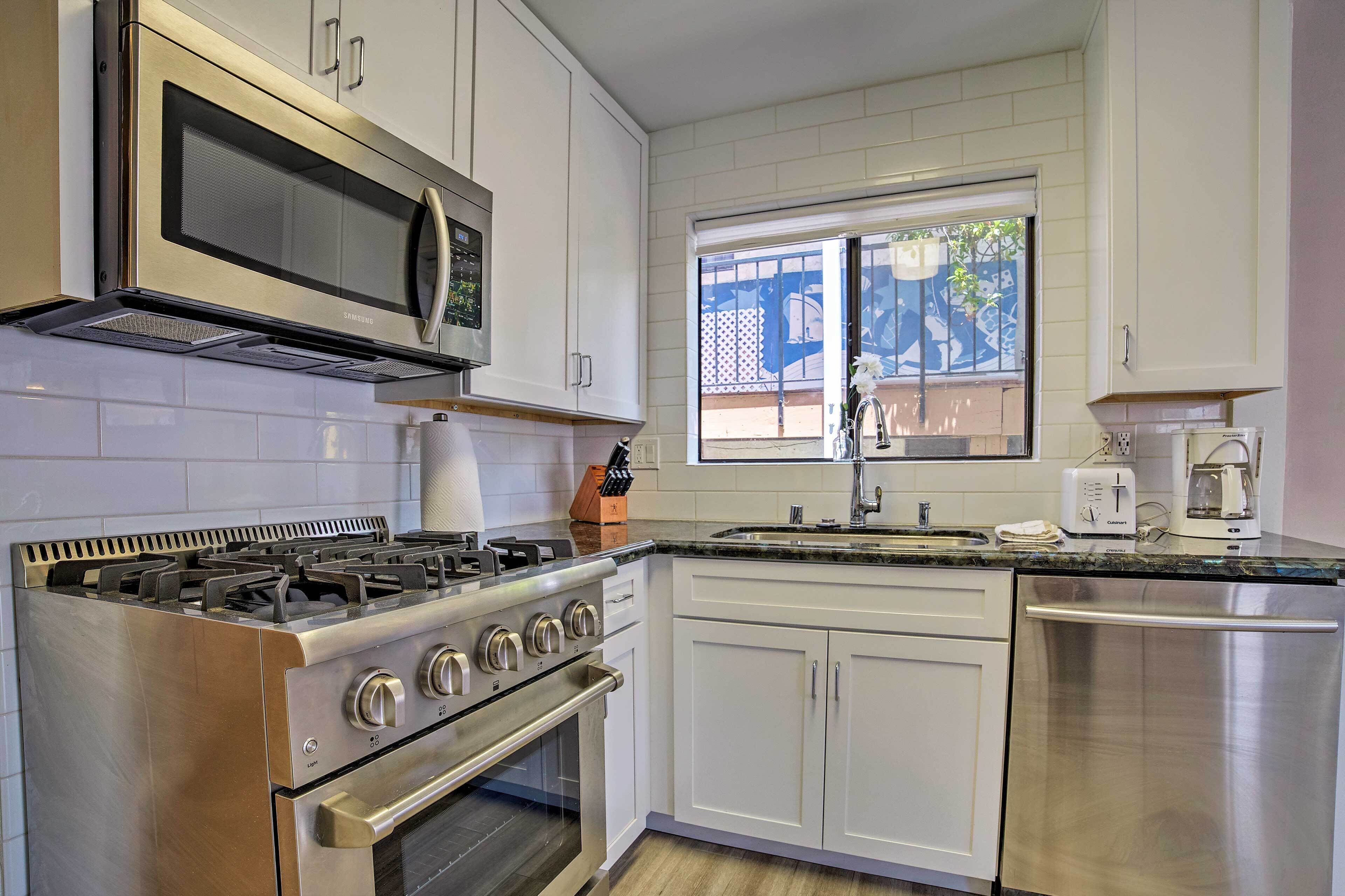 A modern kitchen with stainless steel appliances, white cabinetry, and a window providing natural light.