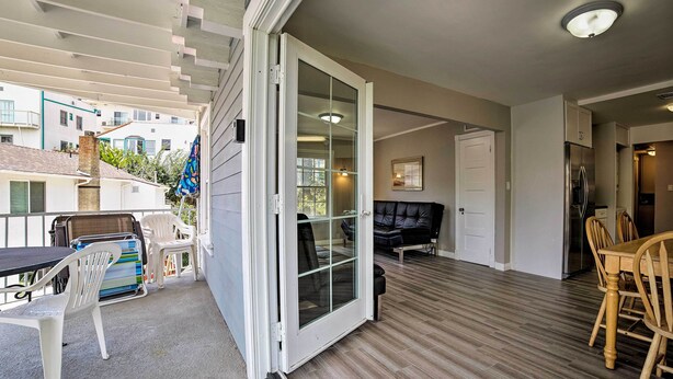 Een ruim balkon met een schuifdeur, een eethoek met houten stoelen, en een keuken met een koelkast.