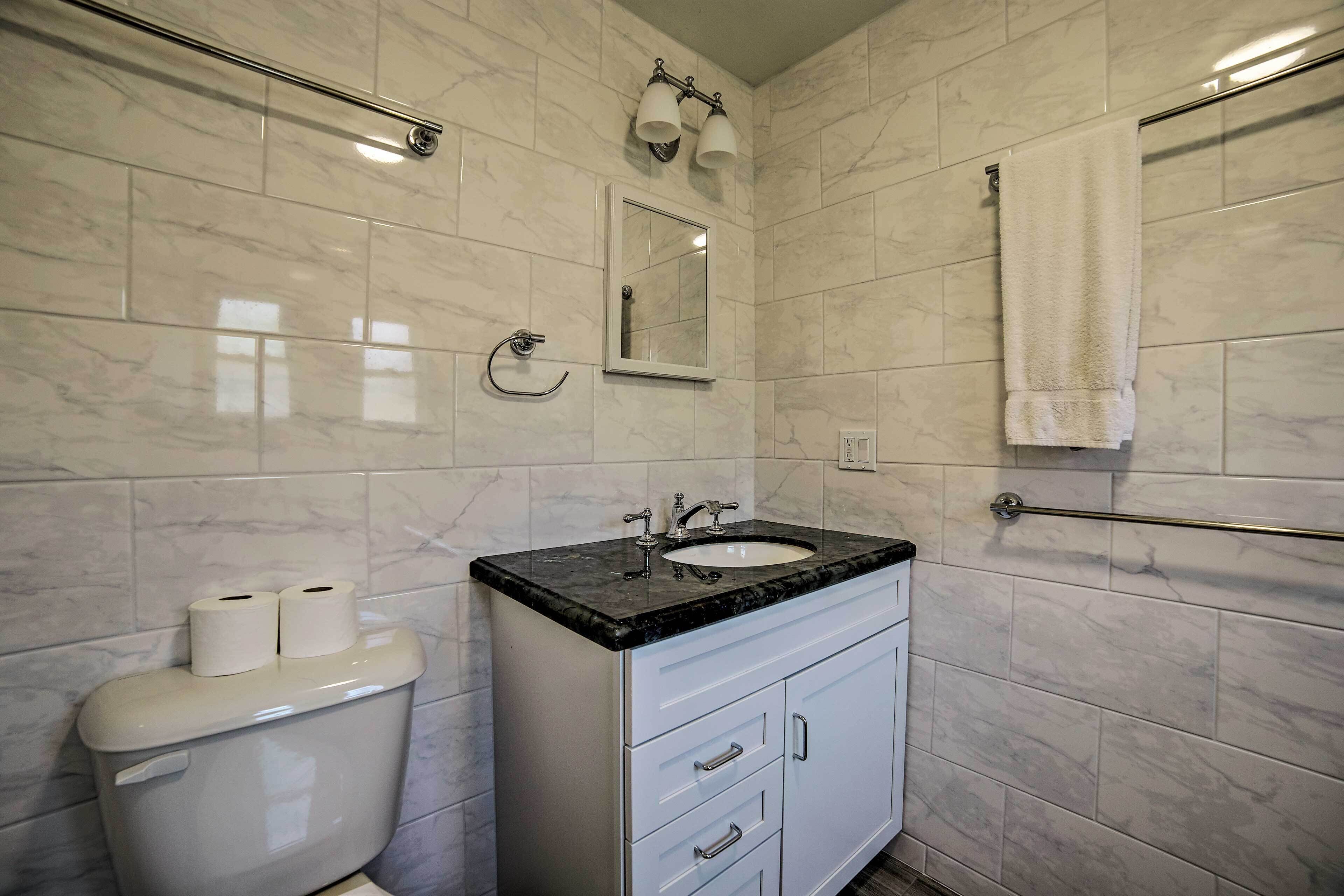 A bathroom with a toilet, sink, and mirror.
