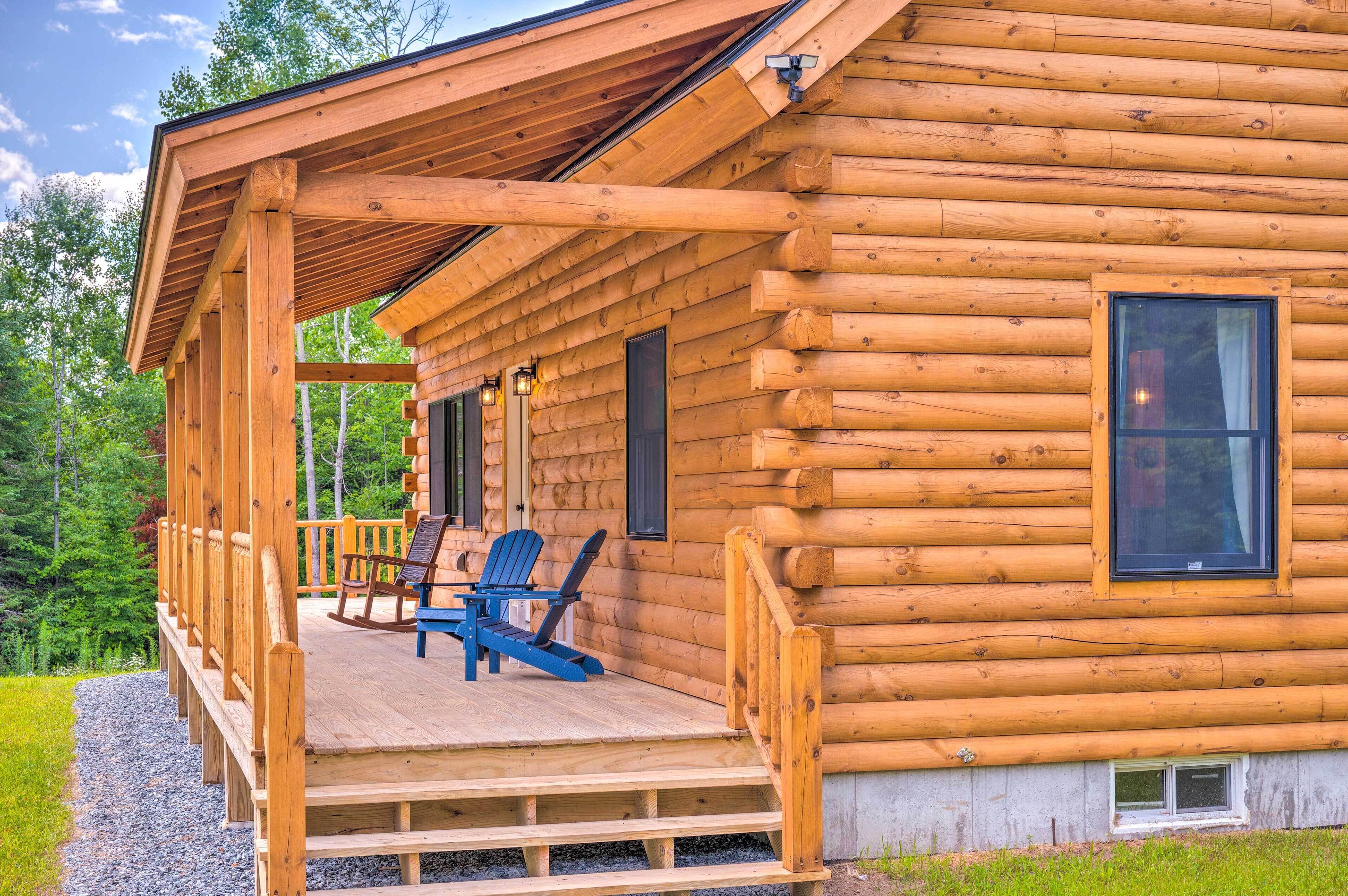 Une cabane en rondins avec une véranda, deux fauteuils à bascule et une petite fenêtre.