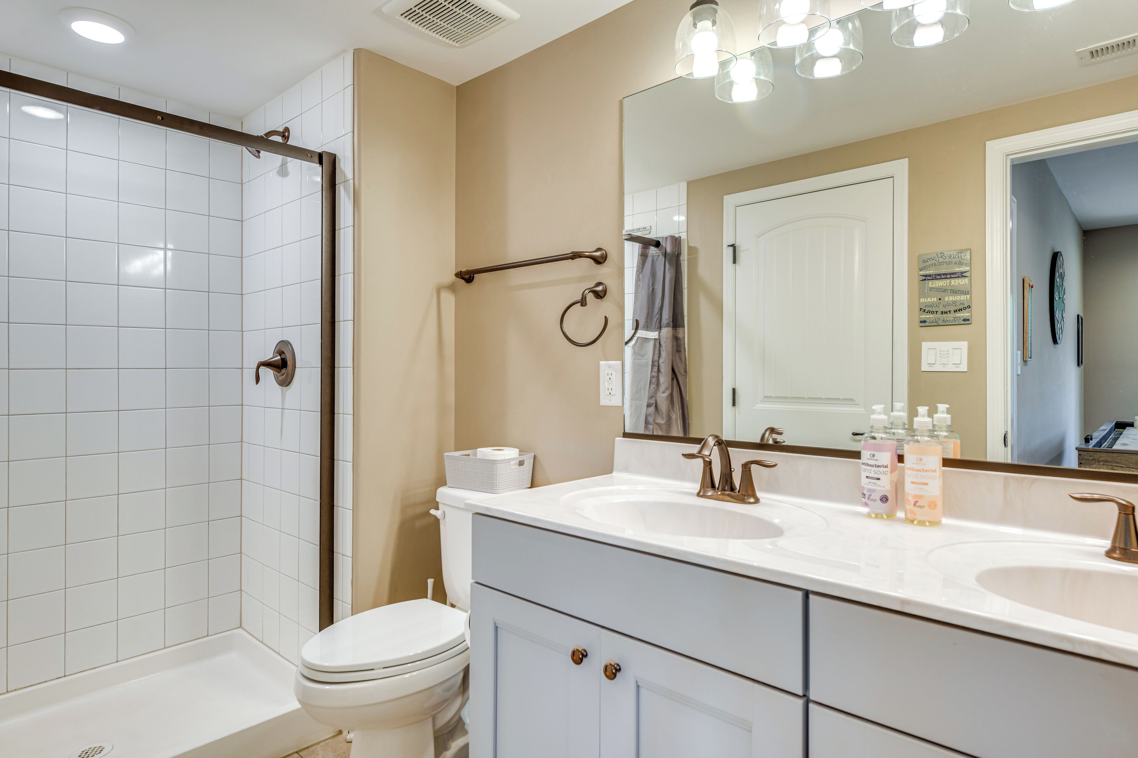 Une salle de bain moderne équipée d’une douche, de toilettes et d’un meuble-lavabo avec deux vasques.