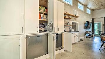 Una cocina con armarios abiertos, un refrigerador y un televisor.
