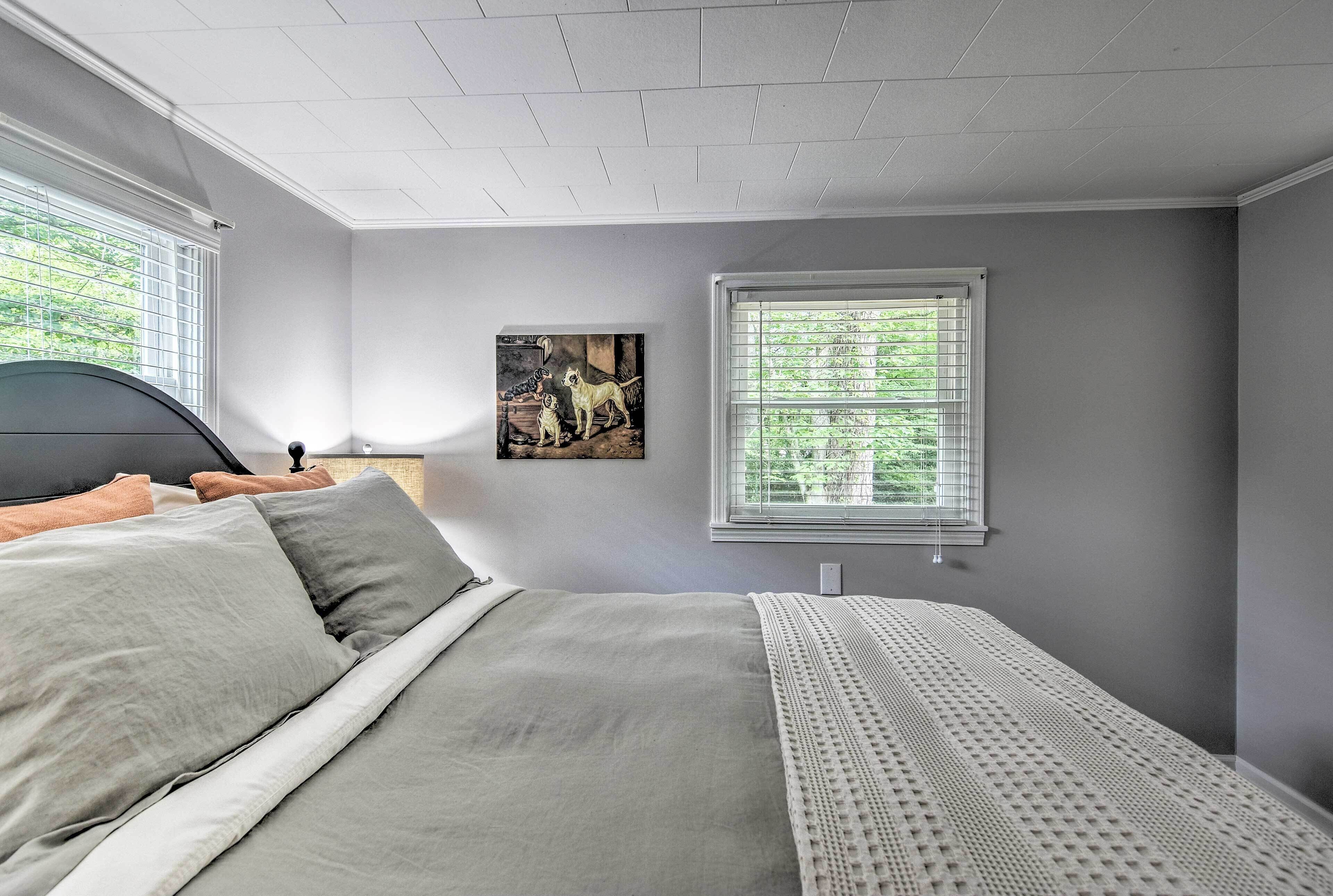 A bedroom with a bed, a window, and a painting on the wall.