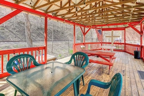A covered outdoor deck with a table and chairs, wooden railings, and a view of a wooded area. - Access to Warrior Trail! ATV Base Camp in Gary (Gary)