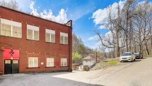 A red brick building with a garage door, a small attached structure, and a paved driveway. - Access to Warrior Trail! ATV Base Camp in Gary (Gary)