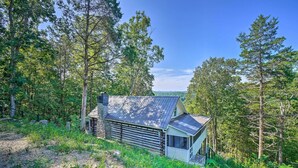 Une cabane rustique avec un toit en métal, entourée d’une forêt dense.