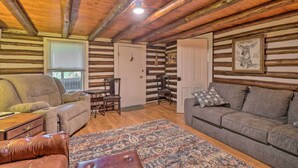 L’intérieur d’une cabane en rondins, avec un canapé, un fauteuil et un tapis à motifs.