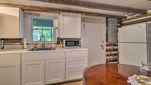 Une cuisine avec des armoires blanches, un four à micro-ondes, un évier et un plafond en bois.