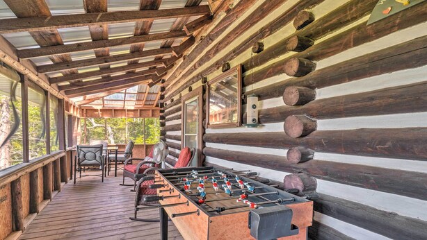 Une terrasse en bois avec un baby-foot, des chaises et une table avec des chaises.