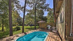 Eine Holzterrasse mit Swimmingpool, umgeben von Bäumen und einem Holzzaun.