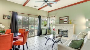 Una sala de estar con chimenea, ventilador de techo y comedor con sillas y una mesa.