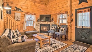 A cozy log cabin interior with a fireplace, wooden walls, a staircase, and a star decoration. - Rustic Rothbury Cabin w/ Resort Amenity Access! (Rothbury)