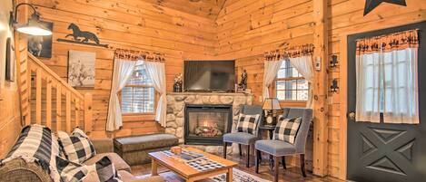 Interior acogedor de una cabaña de troncos con chimenea, paredes de madera, una escalera y una decoración con forma de estrella.