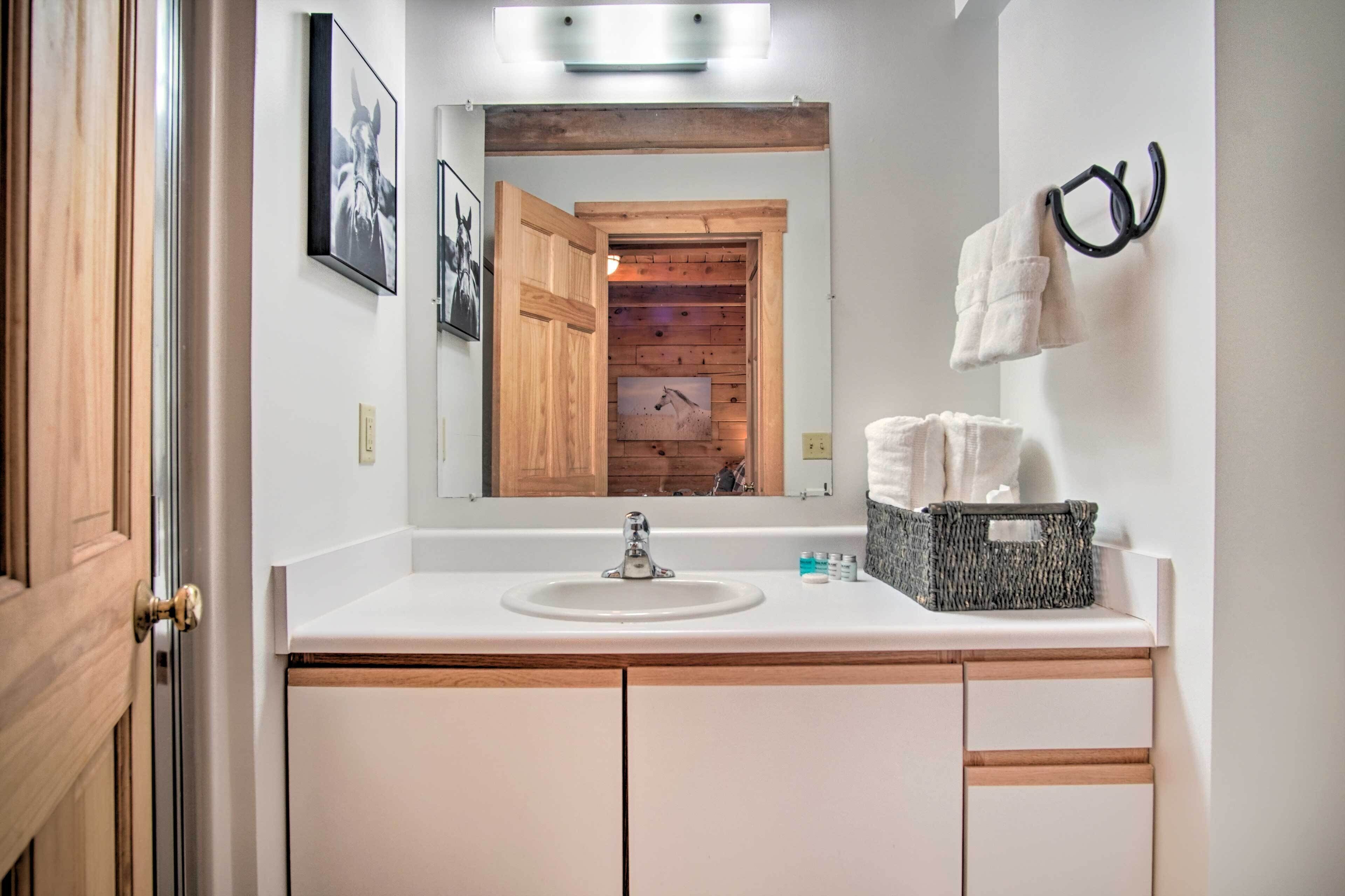 A bathroom with a white sink, wooden cabinets, a mirror, and a towel rack.