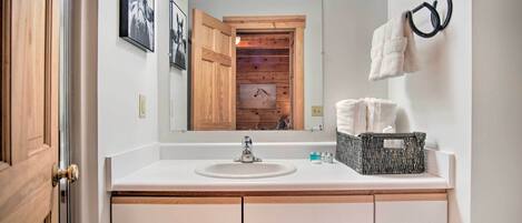 A bathroom with a white sink, wooden cabinets, a mirror, and a towel rack.