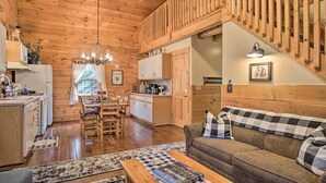 A cozy cabin interior with a wooden ceiling, a dining area, a kitchen, and a living room with a sofa. - Rustic Rothbury Cabin w/ Resort Amenity Access! (Rothbury)