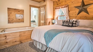 A wooden cabin bedroom with a large bed, a star decoration, a wall-mounted picture, and a window with curtains. - Rustic Rothbury Cabin w/ Resort Amenity Access! (Rothbury)