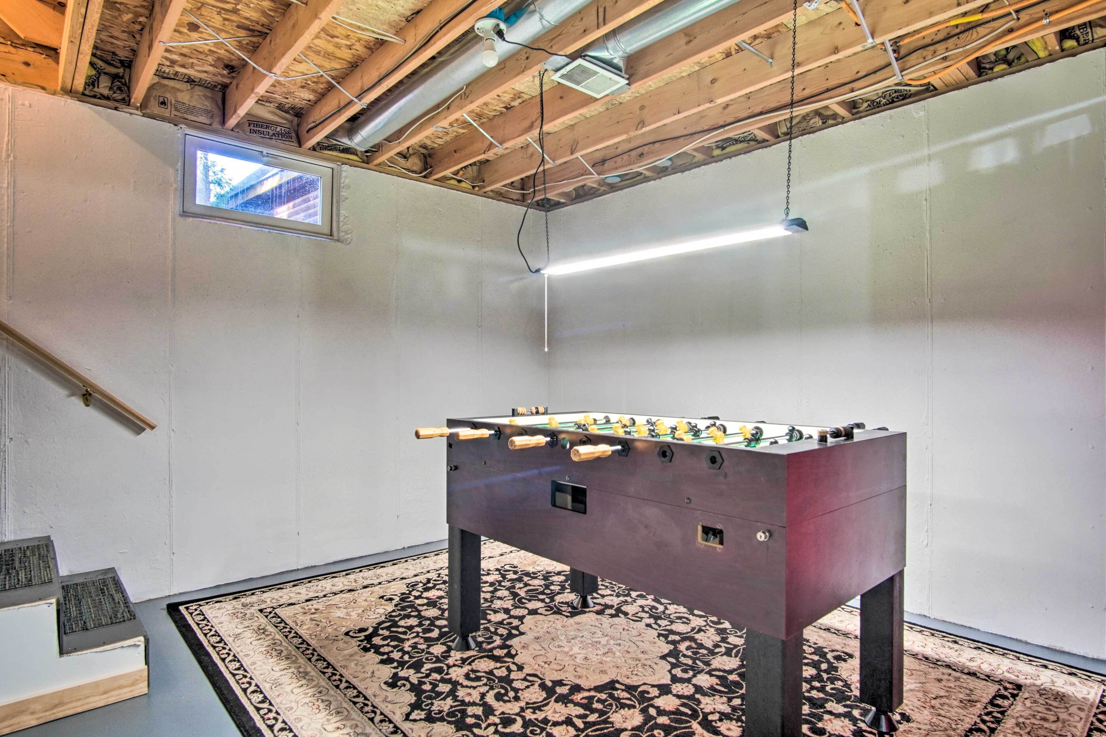 A room with a foosball table, a small window, and a ceiling fan.